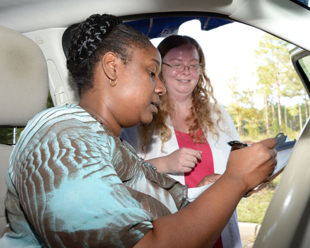 Lisa Johnson, (left) pre-kindergarten teacher, Child Development Center, Marine Corps Logistics Base Albany, completes the process of receiving a new car seat from Alisha Enfinger, MCCS' safety officer and certified child passenger safety technician, at the car seat safety check point at the CDC, Sept. 17.
