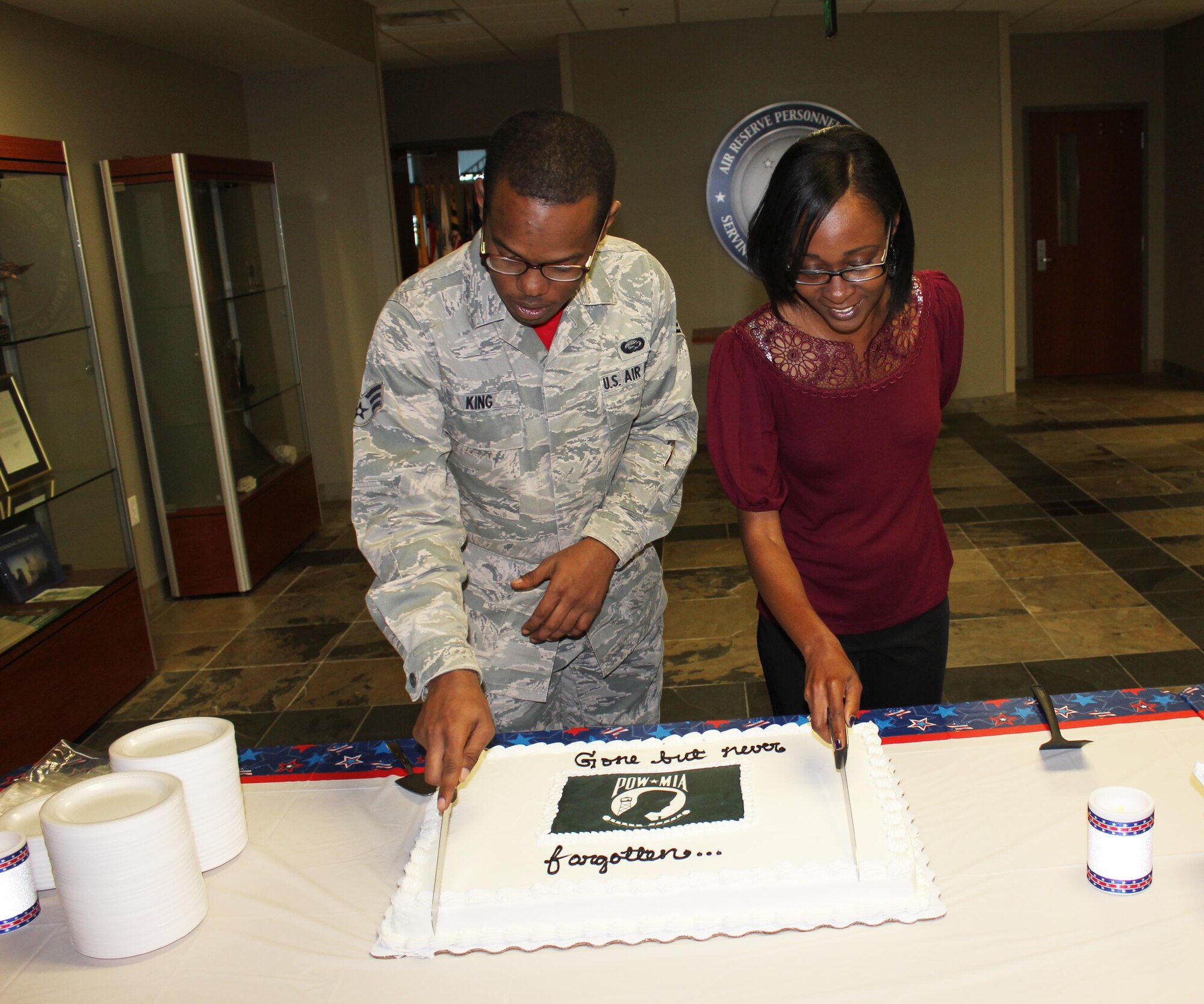 Senior Airman Marqui King, Air Reserve Personnel Center reserve assignment technician, and Nikki Johnson, ARPC promotion eligibility human resources assistant, cut a ceremonial cake in recognition of National POW/MIA Recognition Day Sept. 18, 2015, at the Air Reserve Personnel Center on Buckley Air Force Base, Colo. National POW/MIA Recognition Day is observed around the world on military installations, ships, in state capitals, schools and veterans' facilities on the third Friday in September each year. According to the Defense Prisoner of War/Missing Personnel Office, more than 83,000 Americans are missing from World War II, the Korean War, the Cold War, the Vietnam War and the 1991 Gulf War. For more information, log onto http://www.dpaa.mil/. (U.S. Air Force photos/Tech. Sgt. Rob Hazelett)
