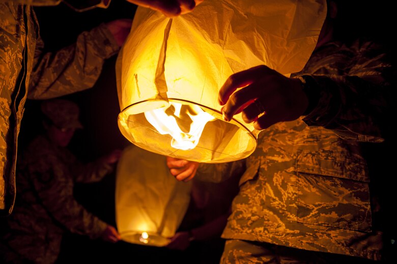 U.S. Air Force Tech. Sgt. Ezequiel Rodriguez, 18th Operations Support Squadron NCO in charge of airfield management , Tech. Sgt. Dustin Troyer, 18th OSS deputy airfield manager, Tech. Sgt. Lisa Rodriguez, 18th OSS deputy airfield manager, and Master Sgt. Mauricio Lopez, 18th Equipment Maintenance Squadron NCO in charge of non-destructive inspection, hold sky lanterns as the significance of the lanterns are explained during the POW/MIA  Sky Lantern Ceremony Sept. 17, 2015, at the Kadena Marina, Kadena Air Base, Japan. The lanterns were lit to honor POWs and MIAs and symbolize hope and remembrance. (U.S. Air Force photo by Airman 1st Class Lynette M. Rolen/Released)