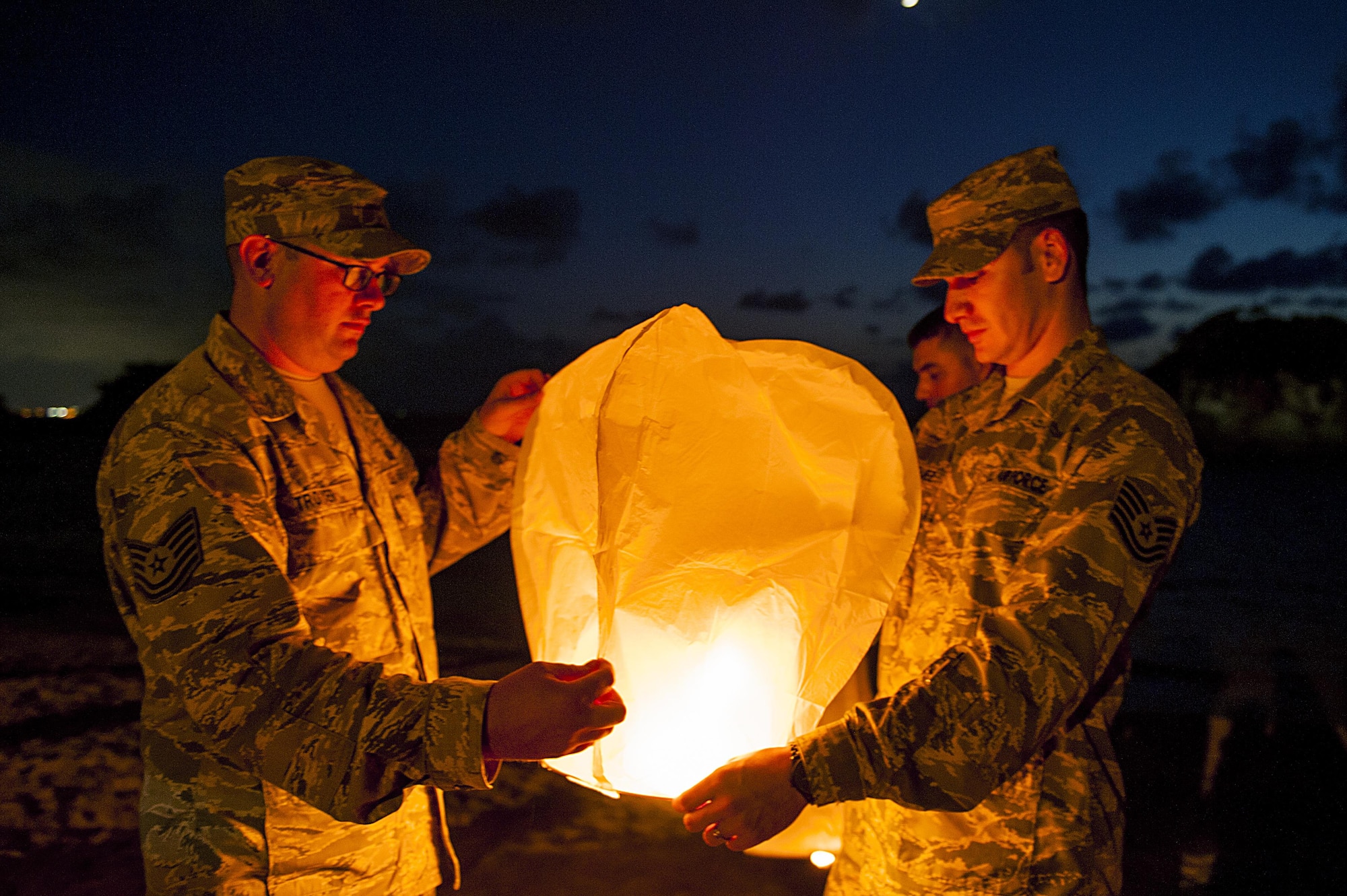 U.S. Air Force Tech. Sgt. Ezequiel Rodriguez, 18th Operations Support Squadron NCO in charge of airfield management and Tech. Sgt. Dustin Troyer, 18th OSS deputy airfield manager, prepare to launch a sky lantern during the POW/MIA Sky Lantern Ceremony Sept. 17, 2015, at the Kadena Marina, Kadena Air Base, Japan. The lanterns were lit in remembrance of POWs and MIAs. (U.S. Air Force photo by Airman 1st Class Lynette M. Rolen/Released)