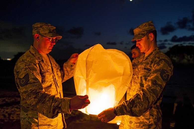 U.S. Air Force Tech. Sgt. Ezequiel Rodriguez, 18th Operations Support Squadron NCO in charge of airfield management and Tech. Sgt. Dustin Troyer, 18th OSS deputy airfield manager, prepare to launch a sky lantern during the POW/MIA Sky Lantern Ceremony Sept. 17, 2015, at the Kadena Marina, Kadena Air Base, Japan. The lanterns were lit in remembrance of POWs and MIAs. (U.S. Air Force photo by Airman 1st Class Lynette M. Rolen/Released)