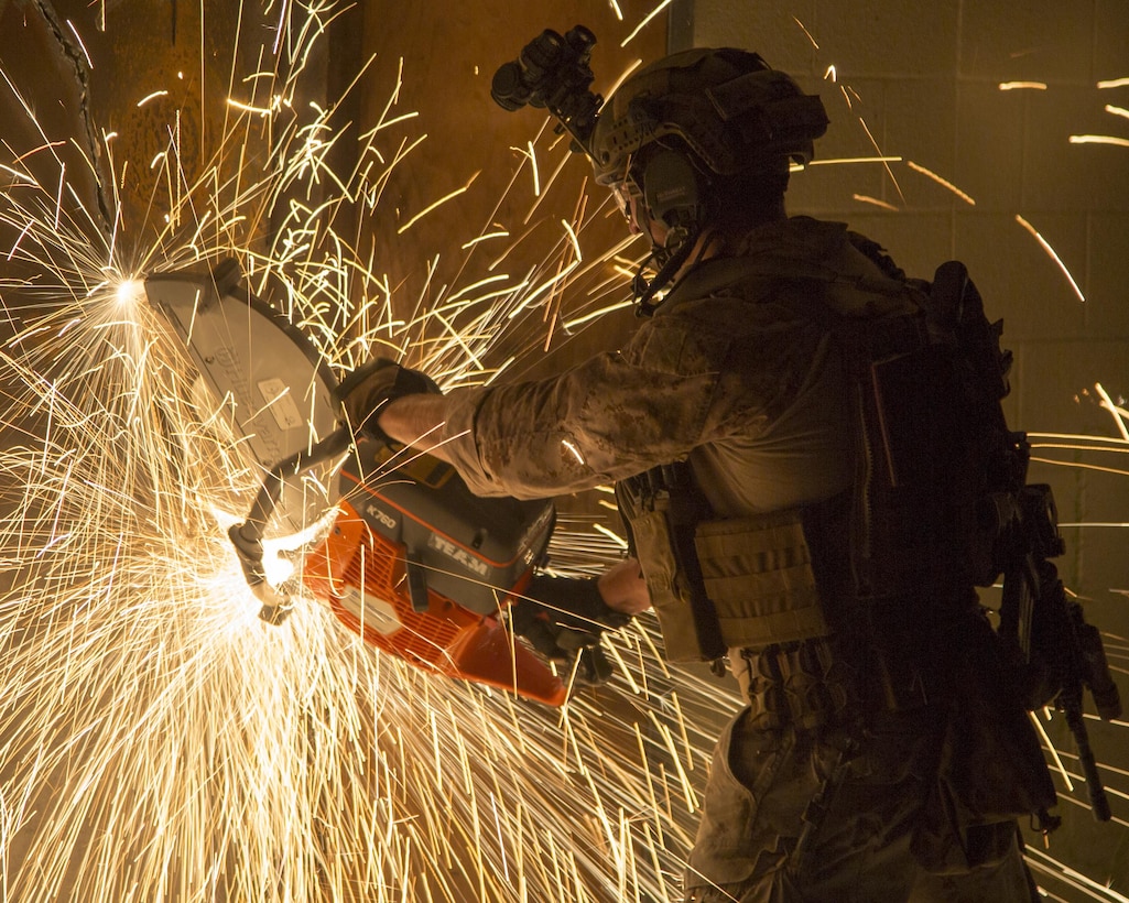A Critical Skills Operator with U.S. Marine Corps Forces Special Operations Command uses a saw to cut through a metal door to gain entry on a building during Marine Special Operation School's Master Breacher's Course, at Stone Bay aboard Marine Corps Base Camp Lejeune, N.C., Aug. 20, 2015. The Master Breacher course instructs Critical Skills Operators on how to overcome obstacles such as walls, fences and doors via a range of breaching methods including mechanical, ballistic, thermal and explosive. (U.S. Marine Corps Photo by Sgt. Scott A. Achtemeier / Released)