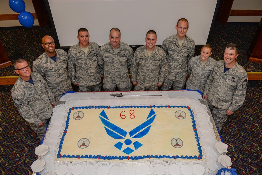 Airmen stand in front of a cake at the Sheppard Club, Sheppard Air Force Base, Texas, during the Air Force’s 68th birthday celebration, Sept. 18, 2015. The Air Force birthday is celebrated each year to reflect on the service and sacrifices of its ancestors. (U.S. Air Force photo/Senior Airman Kyle Gese)