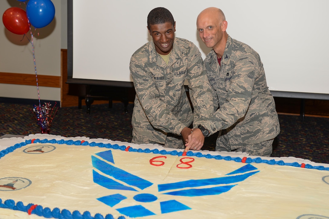 The youngest Airman in Training cuts a cake with Col. Timothy Gillaspie, 82nd Training Wing vice commander, during the 68th Air Force birthday celebration at the Sheppard Club, Sheppard Air Force Base, Texas, Sept. 18, 2015. The Air Force birthday is celebrated each year to reflect on the service and sacrifices of its ancestors. (U.S. Air Force photo/Senior Airman Kyle Gese)