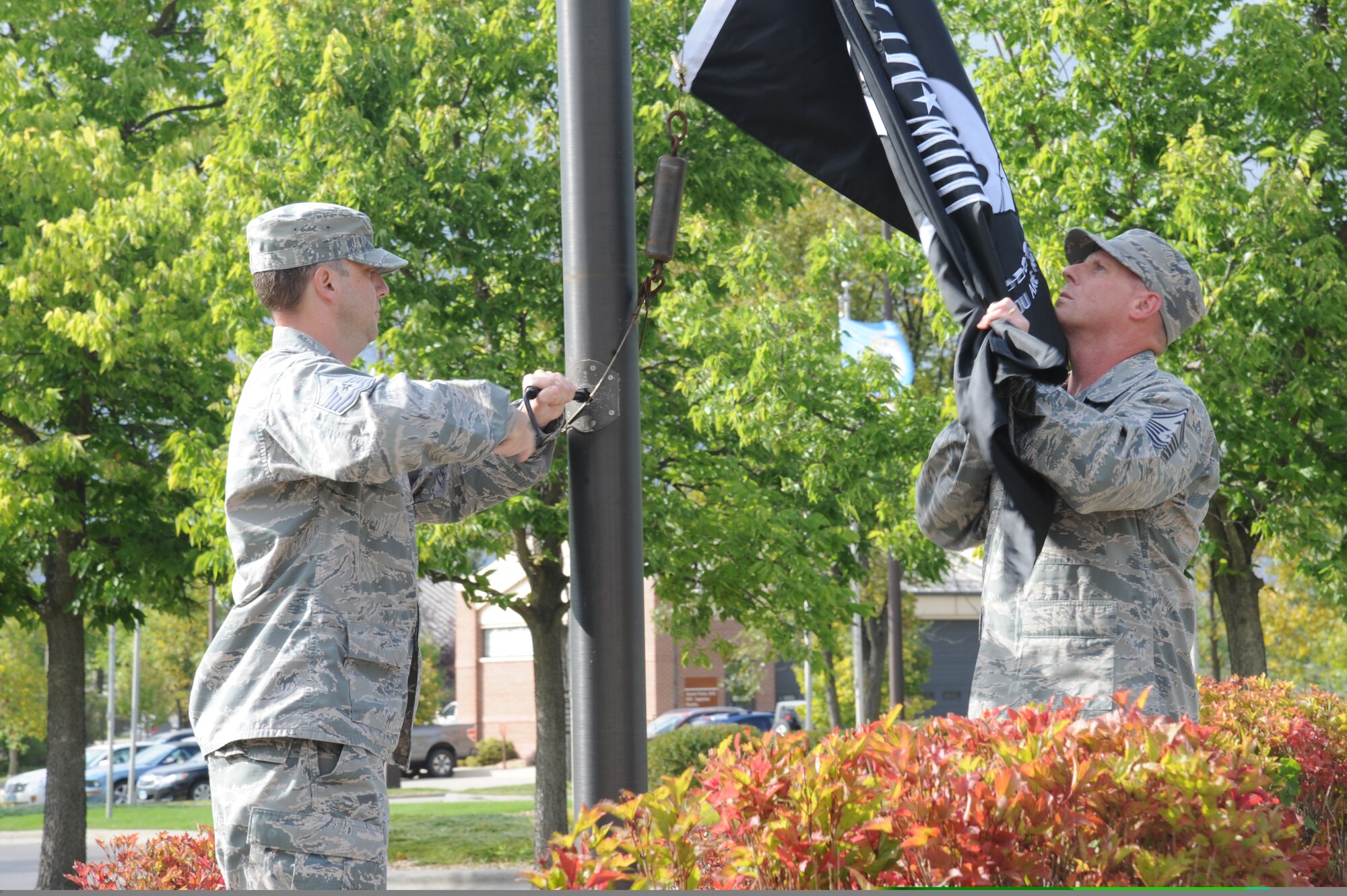 First sergeants Senior Master Sgt. Harold Anderson III, right, and Master Sgt. Stephen Middleton, left, raise the POW/MIA flag during a ceremony Sept. 17, 2015, at Grand Forks Air Force Base, North Dakota. The POW/MIA flag was carried by Grand Forks AFB Airmen for 24-hours prior to the first sergeants raising it to begin the ceremony. (U.S. Air Force photo by Senior Airman Desiree Economides/Released)
