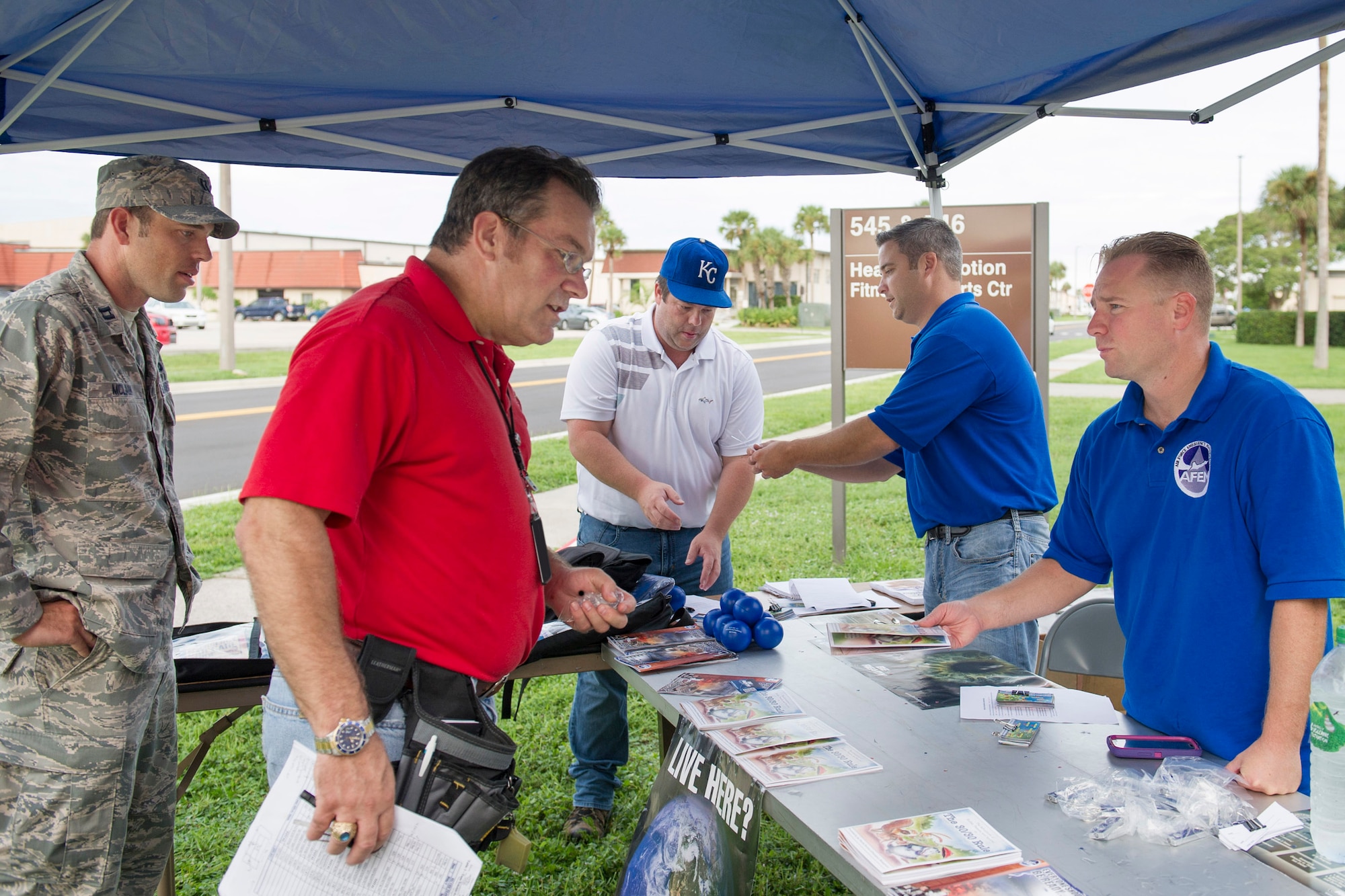 Tech. Sgt. Aaron Burnley, 45th Civil Engineer Squadron emergency manager, right, explains National Preparedness Month to members of team Patrick-Cape in front of the fitness center Sept. 18, 2015, at Patrick Air Force Base, Florida. “The booth is fun a way for the Emergency Management flight to get disaster and emergency awareness out to the base populace,” Burnley said.  (U.S. Air Force photo by Matthew Jurgens/Released)