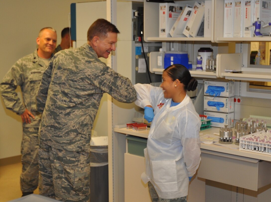Brig. Gen. Wayne Monteith, 45th Space Wing commander, bumps elbows with Senior Airman Alana Takasi, 45th Medical Group lab technician, during an orientation of the 45th MDG Sept. 11, 2015, at Patrick Air Force Base, Florida. (Courtesy photo)