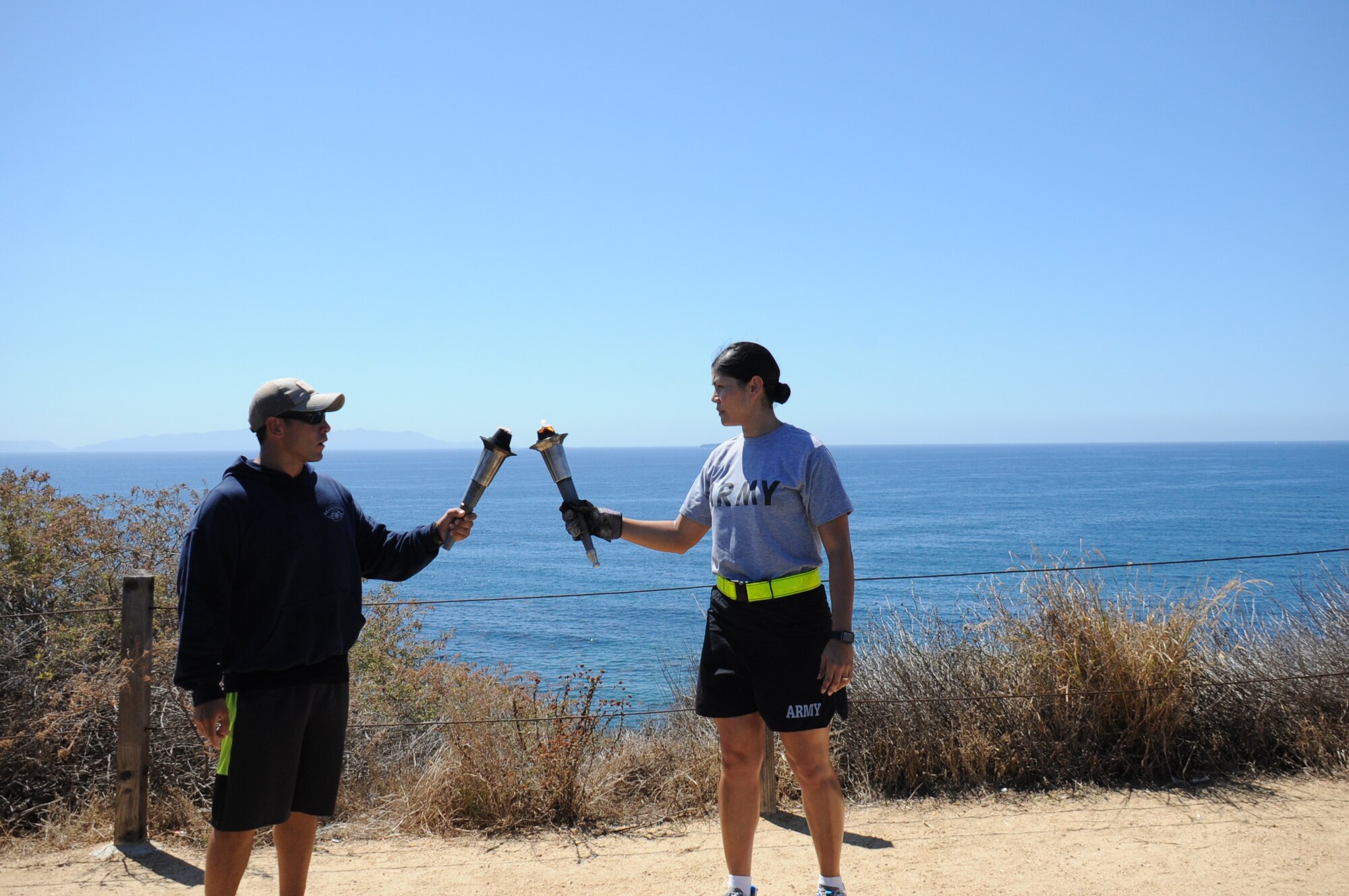 With Catalina Island in the background, a U.S. Coast Guardsman hands off the POW/MIA torch to a U.S. Army soldier on the Palos Verde peninsula during the 24-hour relay in remembrance to honor those who were held captive – and those still missing and unaccounted for during times of armed conflict. (U.S. Air Force photo/Van Ha)