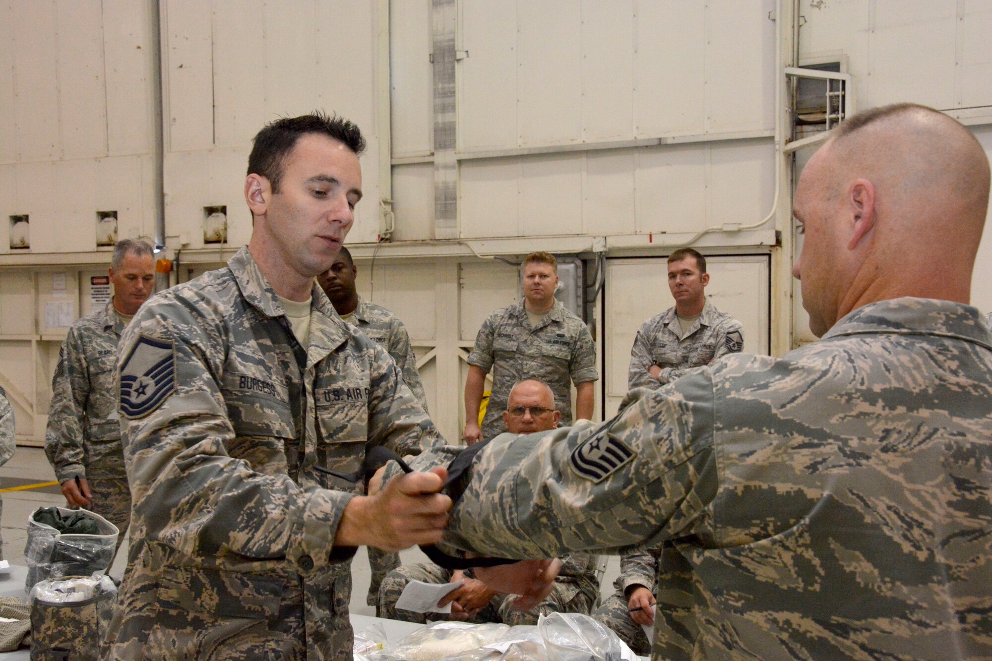 U.S. Air Force Master Sgt. Noah Burgess, education and training coordinator for the 145th Mission Support Group, gives a hands-on demonstration of tourniquet application during the Air Expeditionary Skills Rodeo, held Sept. 13, 2015, in a hangar at the North Carolina Air National Guard Base, Charlotte Douglas International Airport. Nearly 100 NCANG Airmen learned from Burgess and a team of instructors about safe-aid and buddy care during the training which also included actions like treating for shock, patient transportation and how to recognize various ailments. (U.S. Air National Guard photo by Senior Airman Laura Montgomery, 145th Public Affairs/Released)