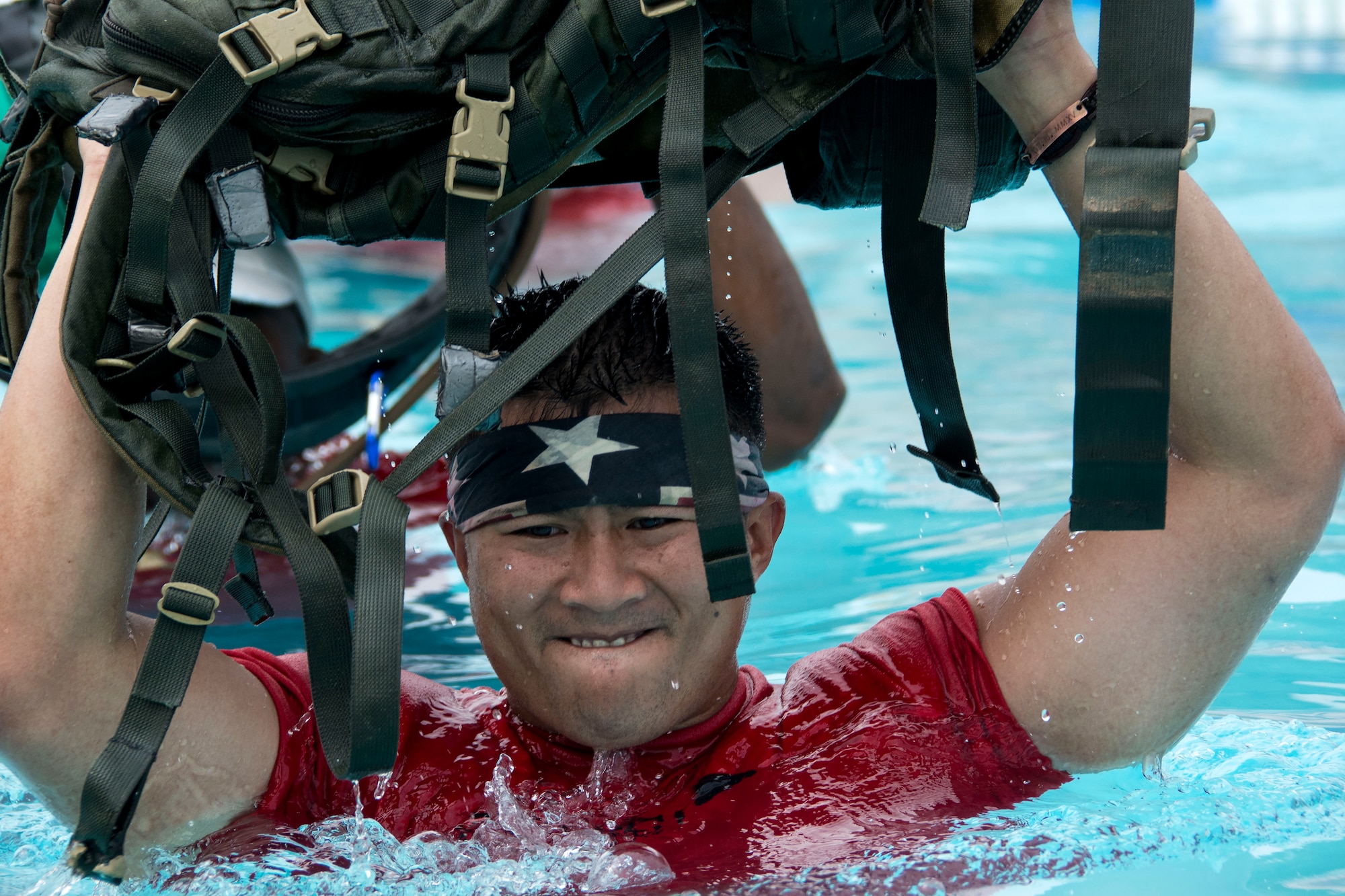 Staff Sgt. Kevin Blevins, 60th Diagnostics and Therapeutics Squadron, holds his rucksack above his head while traversing the base pool during a GoRuck Light Challenge Sept. 12, 2015, at Travis Air Force Base, California. Designed and developed by former United States military special operations personnel, the challenge is meant to provide an introduction to the team-based training found within the special operations community. (U.S. Air Force photo/Senior Airman Charles Rivezzo)