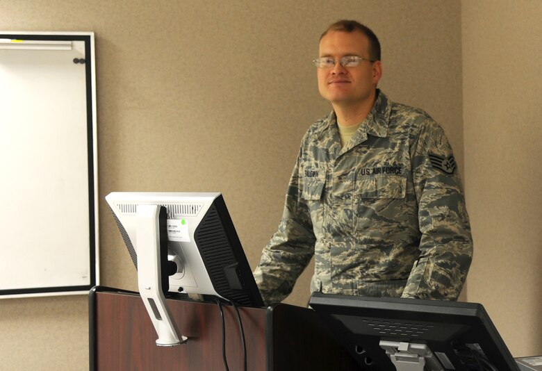 Staff Sgt. Jason Baldwin, 372nd Training Squadron Detachment 27 tactical field terminal instructor, stands at the lecturn where he often teaches Sept. 17, 2015, at Grand Forks Air Force Base, North Dakota. Baldwin is selected as the Warrior of the Week. (U.S. Air Force photo by Senior Airman Desiree Economides/Released)