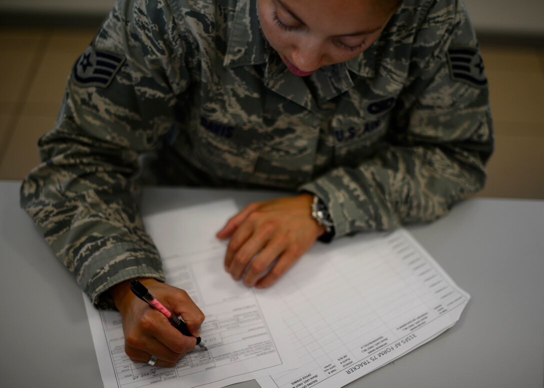 U.S. Air Force Staff Sgt. Porsche Davis, 31st Security Forces Squadron Visitor Control Center NCO in charge, fills out an Air Force Form 75 to grant an individual access to Aviano Air Base, Italy, Sept. 16, 2015. The VCC is in charge of coordinating and granting access to all base visitors. (U.S. Air Force photo by Senior Airman Areca T. Bell/Released)