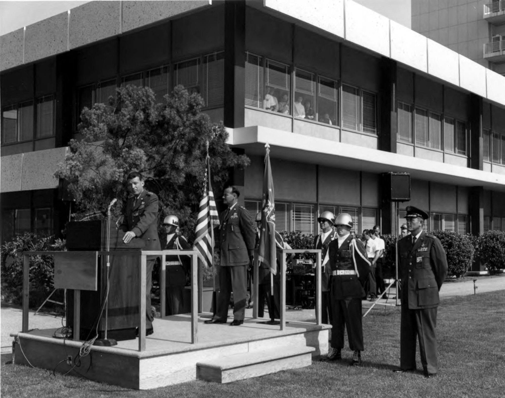 General Bernard A. Schriever, commander of Air Force Systems Command, addresses an assembled crowd in the Area A mall during the dedication of Los Angeles Air Force Station on July 10, 1964. Standing directly behind Gen. Schriever is Maj. Gen. Ben I.Funk, commander of Space Systems Division. Col. Roy Russell, commander of Los Angeles AFS, stands on the far right by the Air Force Honor Guard. (U.S. Air Force photo)