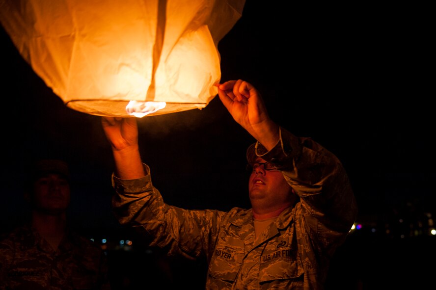 U.S. Air Force Tech. Sgt. Dustin Troyer, 18th Operations Support Squadron deputy airfield manager, releases a sky lantern during the POW/MIA Sky Lantern Ceremony Sept. 17, 2015, at the Kadena Marina, Kadena Air Base, Japan.  The lanterns were lit to remember fellow brothers and sisters in arms who are POWs and MIAs. (U.S. Air Force photo by Airman 1st Class Lynette M. Rolen)