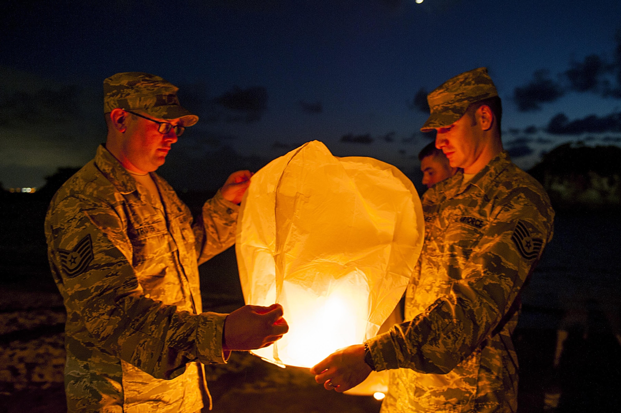 U.S. Air Force Tech. Sgt. Ezequiel Rodriguez, 18th Operations Support Squadron NCO in charge of airfield management and Tech. Sgt. Dustin Troyer, 18th OSS deputy airfield manager, prepare to launch a sky lantern during the POW/MIA Sky Lantern Ceremony Sept. 17, 2015, at the Kadena Marina, Kadena Air Base, Japan. The lanterns were lit in remembrance of POWs and MIAs. (U.S. Air Force photo by Airman 1st Class Lynette M. Rolen)