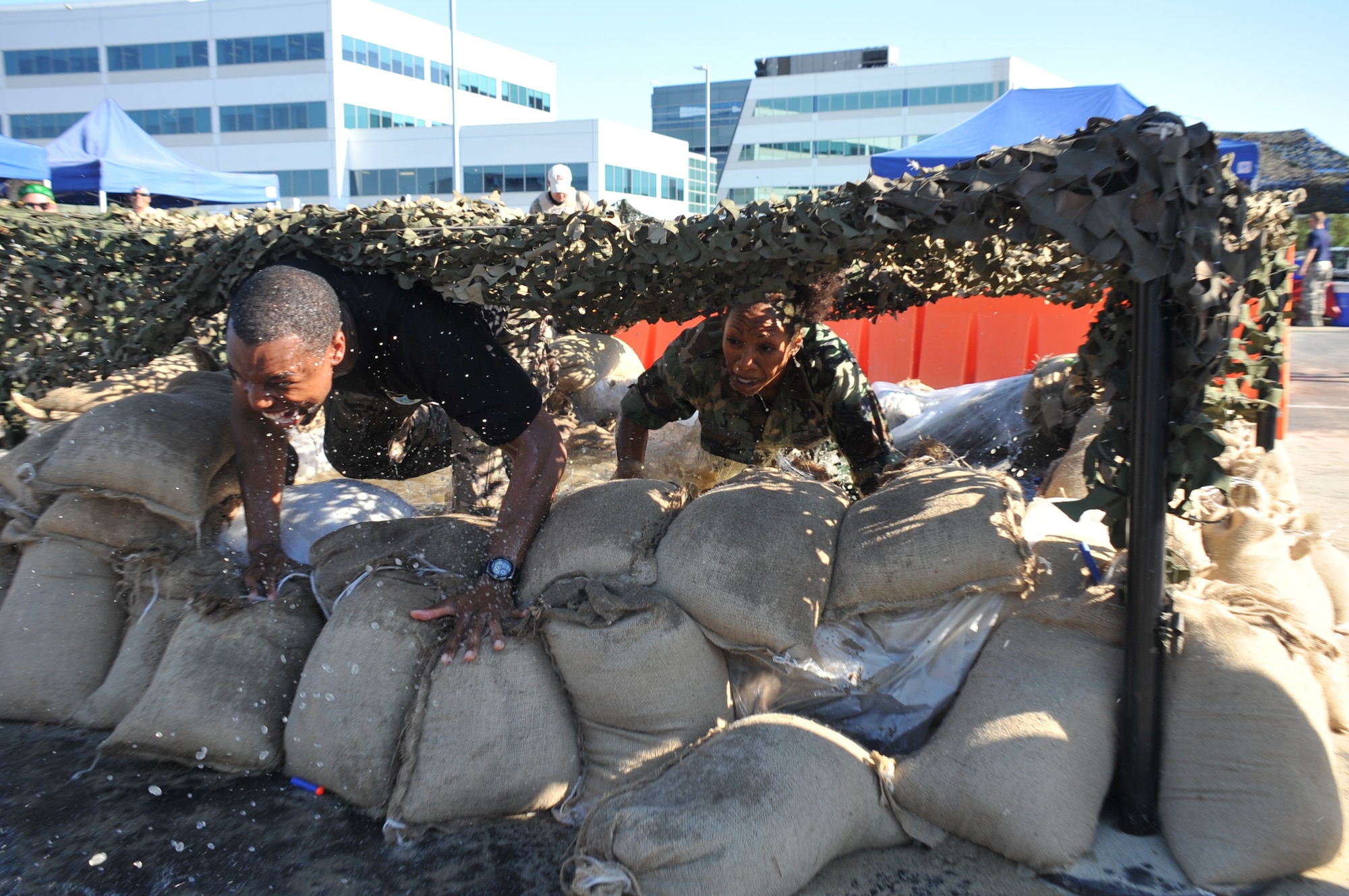 Capt. Nicholas Battle, executive officer to Maj. Gen. Robert McMurry, Space and Missile Systems Center vice commander, and Janell Green, 61st Communications Squadron in her role as Madam Vice of the Mess battle it out on the water and sandbag portion of the obstacle course during the SMC Combat Dining-Out at Los Angeles Air Force Base in El Segundo, Calif. (U.S. Air Force photo/Sarah Corrice)