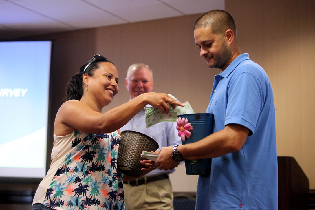 Staff Sgt. Annett Castro, left, puts money in the love bank of Giovanni Hernandez, right, during a Marriage Enrichment Retreat, hosted by 2nd Marine Aircraft Wing Chaplains in New Bern, N.C., Sept. 19, 2015. Forty couples took part in the two-day retreat to rekindle their bond with one another. The love bank is a physical representation for rewarding positive actions by each partner. Castro is an assistant individual material readiness list asset manager for Marine Aircraft Group 29. (U.S. Marine Corps photo by Lance Cpl. Jason Jimenez/Released)