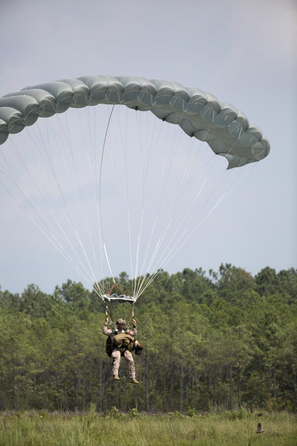A Marine Raider with U.S. Marine Corps Forces, Special Operations Command, prepares to land after parachuting with a Multi-Purpose Canine aboard Marine Corps Base Camp Lejeune, N.C., Sept. 10, 2015. As MARSOC continues to demonstrate their versatile capabilities, MPC handlers with the command are preparing their canines to maneuver in new areas of operation. 