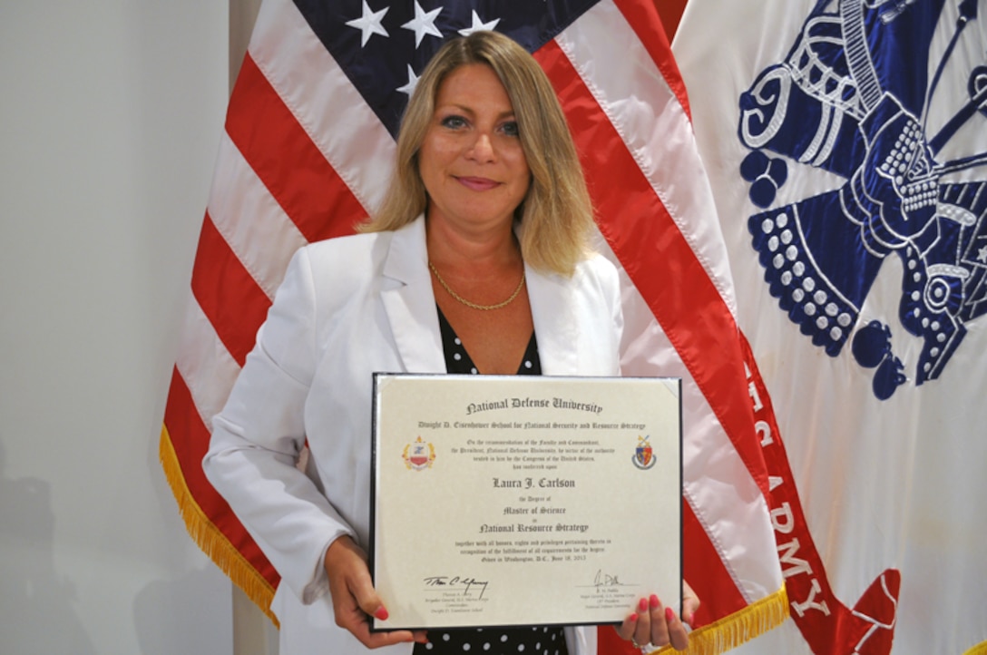Defense Logistics Agency Energy Chief and Program Manager of Installation Energy's Renewables and Energy Savings Performance Based Contracting Laurie Carlson stands with her diploma from the National Defense University where she earned a Master of Science from the Dwight D. Eisenhower School and a Senior Acquisition Certificate from the Defense Acquisition University June 18.
