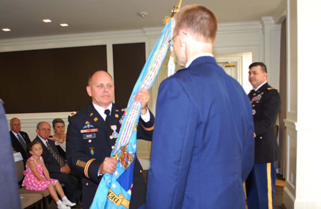 Outgoing Defense Logistics Agency Energy Americas Commander Army Col. Ronald Ross hands the flag to DLA Energy Commander Air Force Brig. Gen. Mark McLeod as he turns over responsibility of the region to Army Col. Craig Simonsgaard during a change of command ceremony in Houston, July 9.