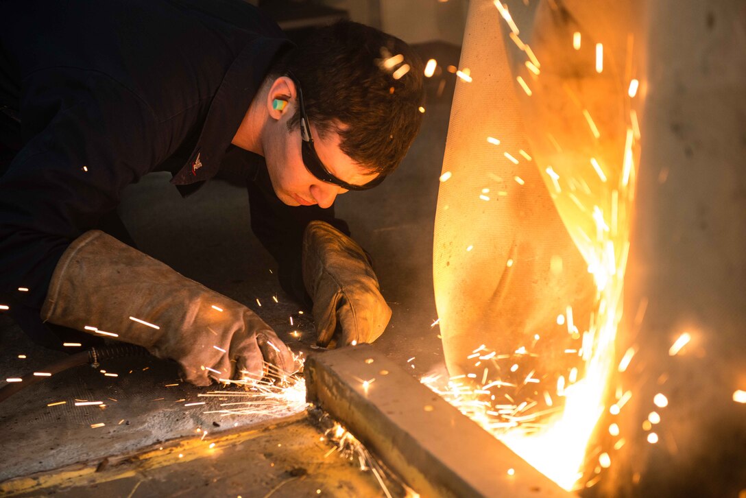 Navy Petty Officer 3rd Class Devin White removes excess deck metal aboard the aircraft carrier USS John C. Stennis in Bremerton, Wash., Sept. 18, 2015. The John C. Stennis is in port training for future deployments.  White is a hull maintenance technician. U.S. Navy photo by Petty Officer 3rd Class Christopher Frost

