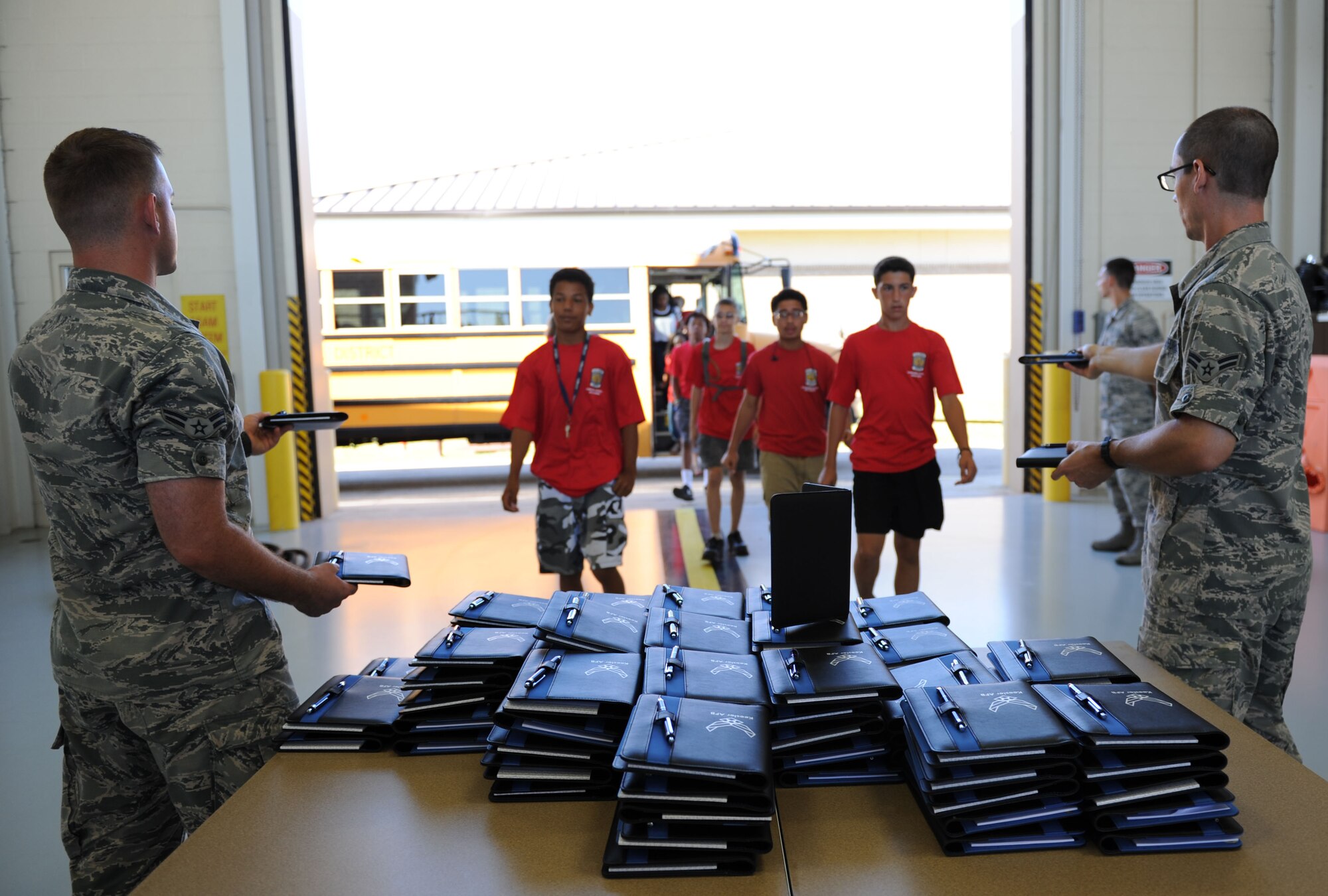 Airmen 1st Class Joshua Moorehead and Joseph Webb, 338th Training Squadron students, hand out notebooks to students from Harrison Central High School as they arrive to the STEM (science, technology, engineering and mathematics) Diversity Outreach Day Sept. 18, 2015, at the fuel cell hangar, Keesler Air Force Base, Miss. The event consisted of 10 Mississippi gulf coast high school Junior ROTC units and science students viewing a staged crime scene, participating in a “brainiacs” test and visiting informative booths about Air Force opportunities and accession requirements with an emphasis on STEM. (U.S. Air Force photo by Kemberly Groue)