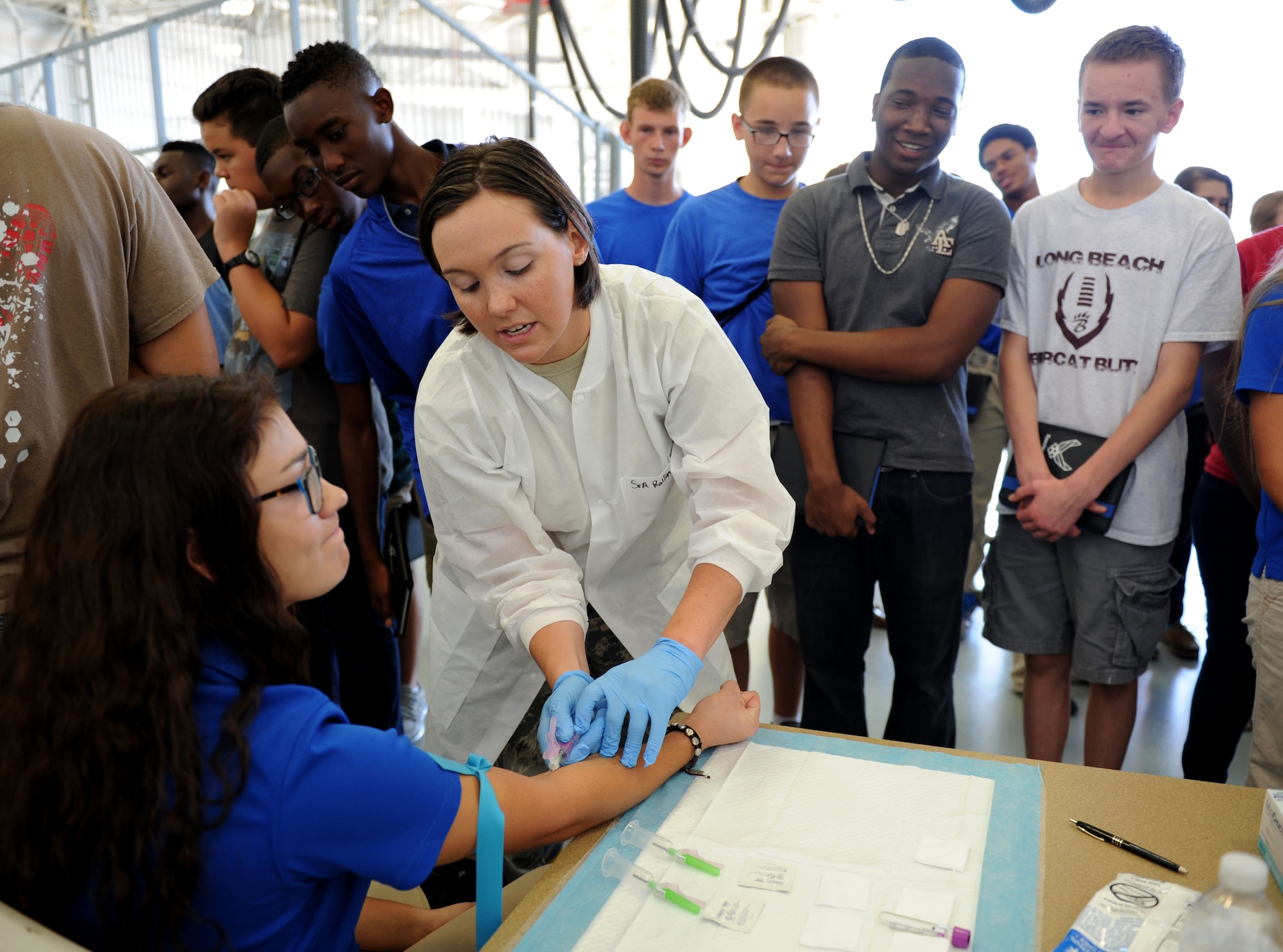 Senior Airman Dana Rollins, 81st Diagnostics and Therapeutics Squadron medical lab technician, demonstrates how to draw blood during the STEM (science, technology, engineering and mathematics) Diversity Outreach Day Sept. 18, 2015, at the fuel cell hangar, Keesler Air Force Base, Miss. The event consisted of 10 Mississippi gulf coast high school Junior ROTC units and science students viewing a staged crime scene, participating in a “brainiacs” test and visiting informative booths about Air Force opportunities and accession requirements with an emphasis on STEM. (U.S. Air Force photo by Kemberly Groue)