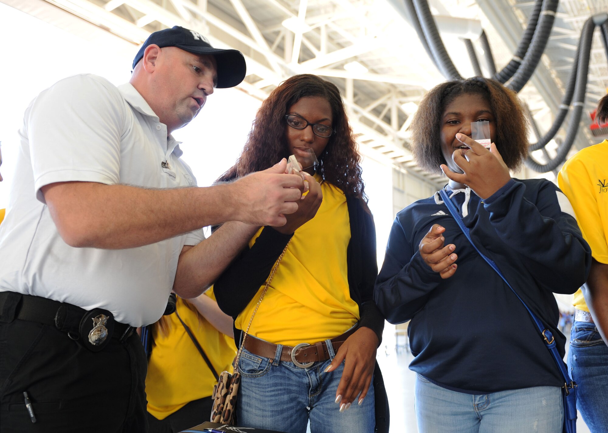 Master Sgt. Douglas Wickline, 81st Security Forces Squadron investigations superintendent, demonstrates how to lift fingerprints from an object to Barbie Burton and Destiny Dean, Gautier High School students, during the STEM (science, technology, engineering and mathematics) Diversity Outreach Day Sept. 18, 2015, at the fuel cell hangar, Keesler Air Force Base, Miss. The event consisted of 10 Mississippi gulf coast high school Junior ROTC units and science students viewing a staged crime scene, participating in a “brainiacs” test and visiting informative booths about Air Force opportunities and accession requirements with an emphasis on STEM. (U.S. Air Force photo by Kemberly Groue)