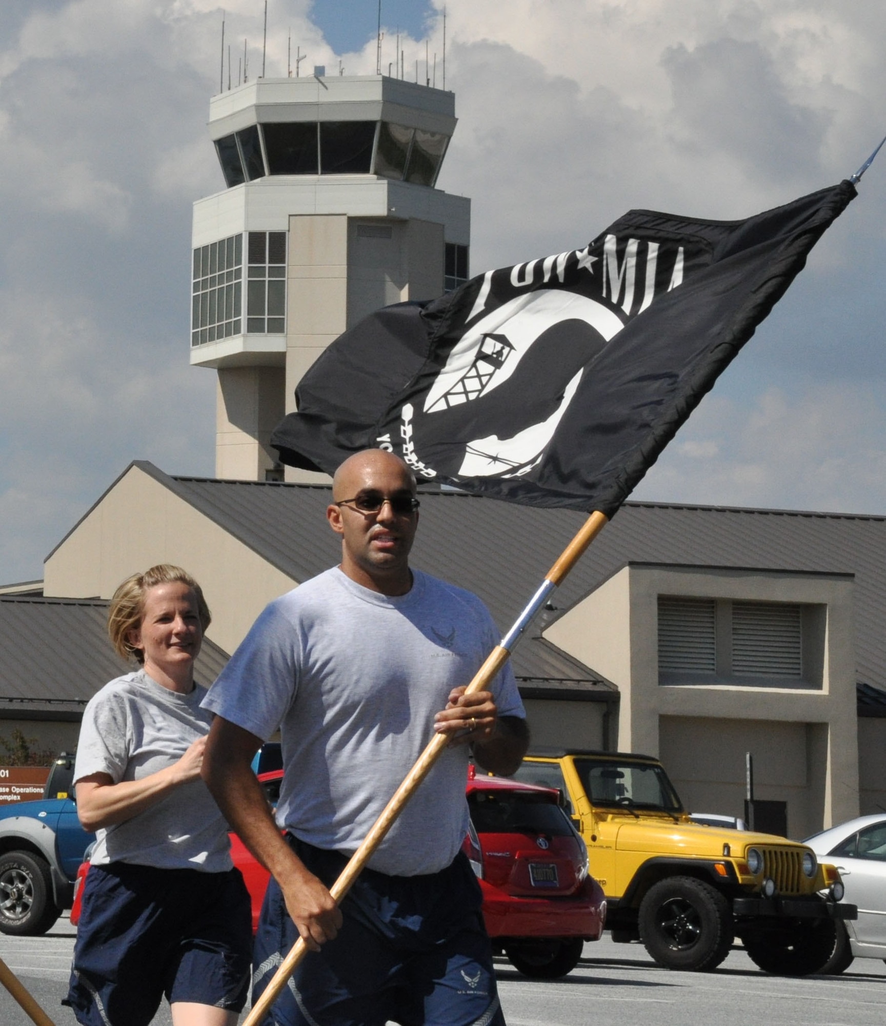 Capt. Jason Lowrey (right) and 1st Lt. Deborah Hautanen, both 512th Airlift Wing staff members, run laps around the base flag pole carrying the prisoner-of-war flag as part of Team Dover's observance of 2015 POW/MIA Recognition Day Sept.18, 2015, at Dover Air Force Base, Del. The 18th marked the last day of 2015 POW/MIA Recognition Week when Americans across the country held local ceremonies remembering past and present American prisoners of war and missing in action. (U.S. Air Force photo/Staff Sgt. Joe Yanik)
