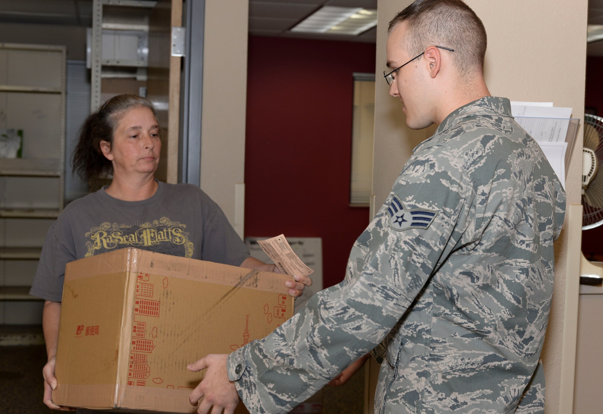 Kim Thompson, 2nd Communications Squadron assistant postal center manager, gives a package to Senior Airman Justin Hammitt, 2nd CS network operations technician at Barksdale Air Force Base, La., Sept. 3, 2015. The postal center requires picture identification and signature from anyone retrieving a package to verify the owner has received their property.  (U.S. Air Force photo/Senior Airman Amanda Morris)