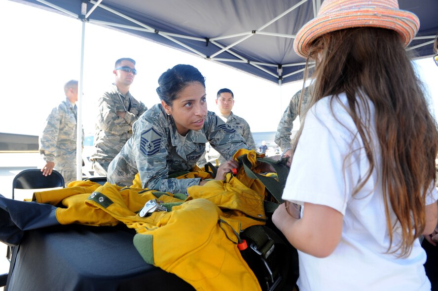 Master Sgt. Vanessa Hernandez-Price, a full-pressure suit technician with the 9th Physiological Support Squadron, Beale Air Force Base, California, demonstrates the suits capabilities to a young spectator during an air show at Joint Base Andrews, Maryland, Sep. 19, 2015. The full-pressure is worn by U-2 Dragon Lady pilots who frequently fly at the edge of space. (U.S. Air Force photo by Senior Airman Bobby Cummings/Released) 