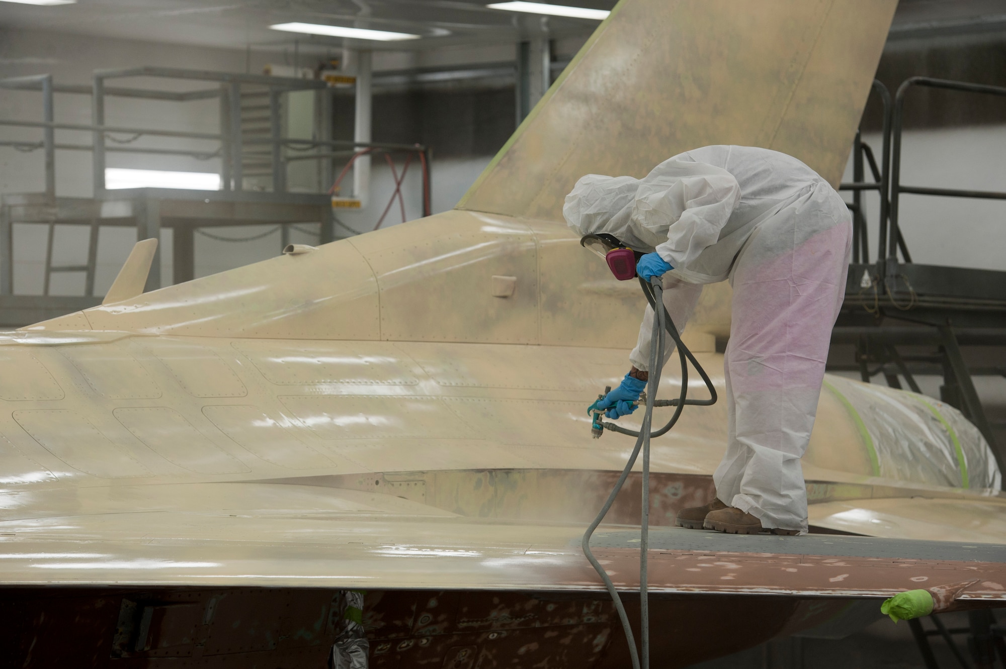 J.J. Ruddell, 57th Maintenance Group corrosion shop aircraft painter, sprays primer on an F-16 Fighting Falcon inside a temperature-controlled building on Nellis Air Force Base, Nev., Sept. 9, 2015. The corrosion shop will do approximately 12 to 15 full paint jobs per year. (U.S. Air Force photo by Airman 1st Class Mikaley Kline)