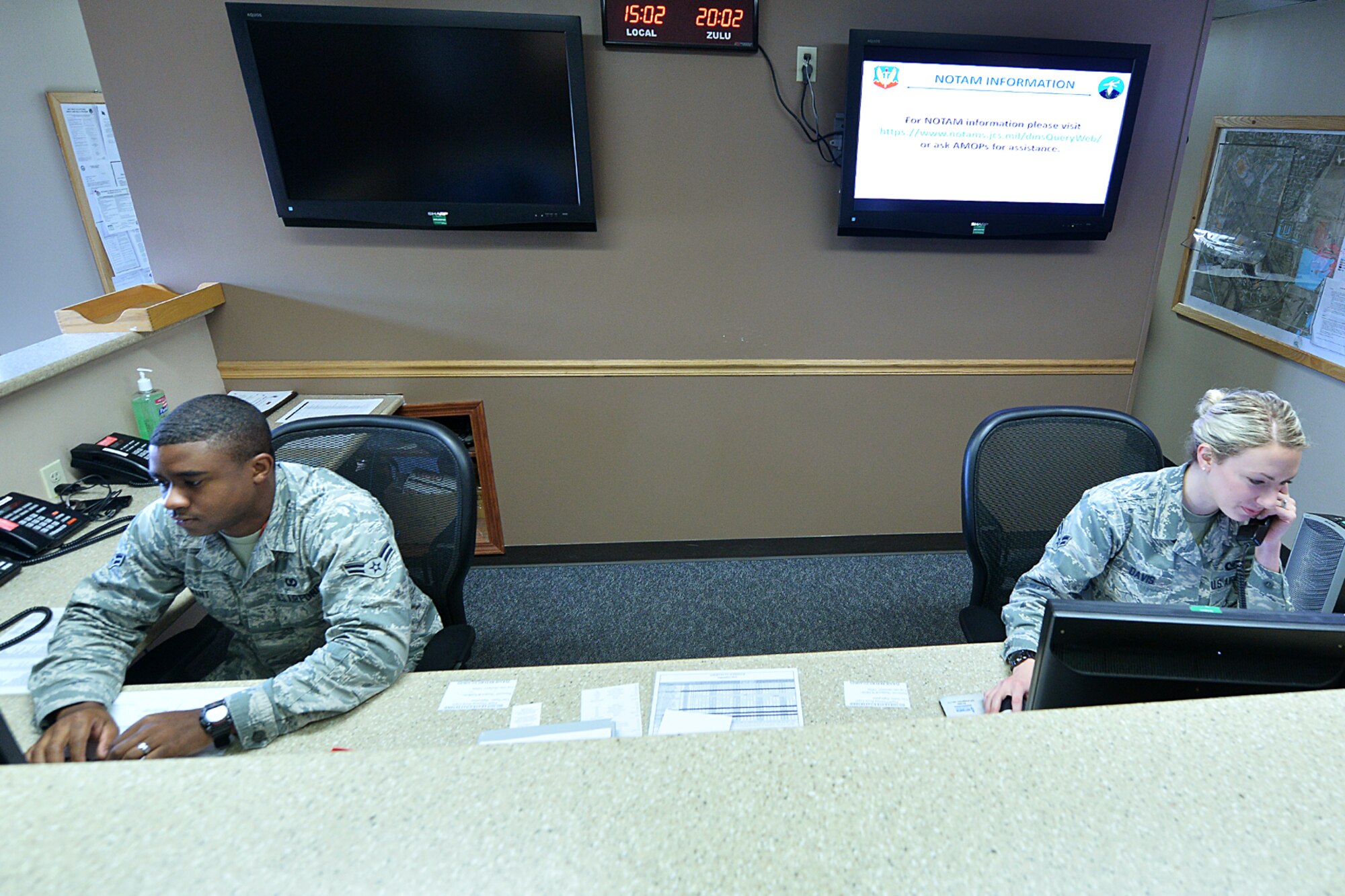 U.S. Air Force Airman 1st Class Justice Grant and U.S. Air Force Airman 1st Class Emily Davis, members of the 55th Operations Support Squadron's airfield management operations team, work out of base operations Sept. 21. Recently, Davis discovered an overturned vehicle and its passenger lying near the flightline during one of her nightly lighting inspections. Her quick actions may have saved a man's life. (Photo by Charles Haymond)