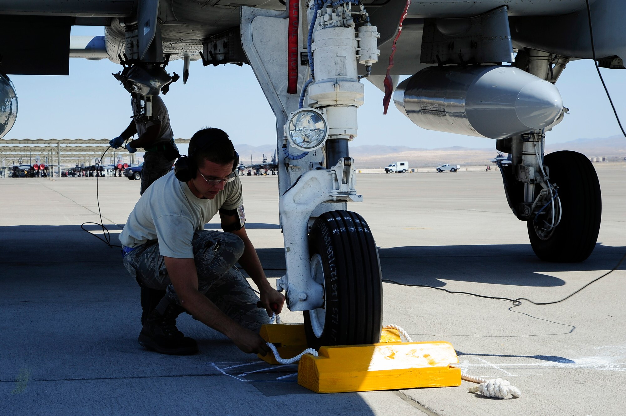 U.S. Air Force Senior Airman Yevgeniy Sokolov, 355th Aircraft Maintenance Squadron crew chief, places chalks around the front tire of an A-10 Thunderbolt II after the aircraft landed at Nellis Air Force Base, Nev., Sept. 10, 2015. More than 100 personnel and eight A-10s from Davis-Monthan AFB, Ariz., are participating in Green Flag-West 15-10, an advanced, realistic, and relevant air to surface training exercise. (U.S. Air Force photo by Senior Airman Betty R. Chevalier/Released)