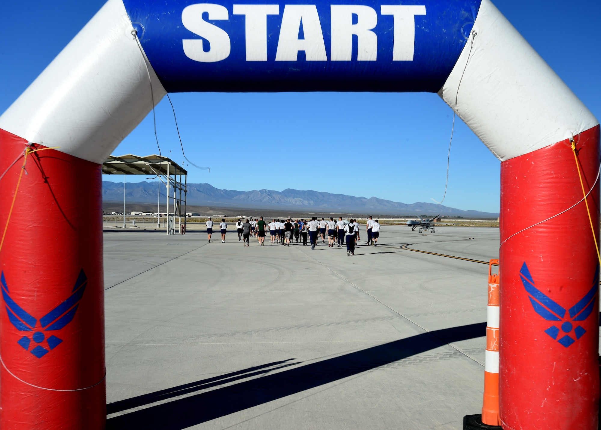 Airmen of the 432nd Wing/432nd Air Expeditionary Wing run passed the start line of the 432nd Maintenance Group Golden Bolt 5K run aimed at raising awareness on the effects foreign object debris can have on aircraft and equipment at Creech Air Force Base, Nevada, Sept 14, 2015. (U.S. Air Force photo by Staff Sgt. Adawn Kelsey)  