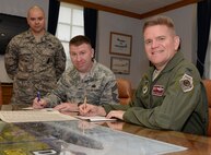 U.S. Air Force Col. Thomas D. Torkelson, right, 100th Air Refueling Wing commander, and U.S. Air Force Chief Master Sgt. Chad W. Bickley, center, 100th Mission Support Group superintendent, prepare to sign Combined Federal Campaign donation forms in Torkelson’s office with U.S. Air Force Master Sgt. Christopher Carrier, 100th Security Forces Squadron NCO in charge of operations support, Sept. 21, 2015, on RAF Mildenhall, England. The CFC is a voluntary program which provides federal employees the opportunity to donate to charities through payroll deductions or a one-time payment. The campaign will run through Nov. 20, 2015. (U.S. Air Force photo by Gina Randall/Released)