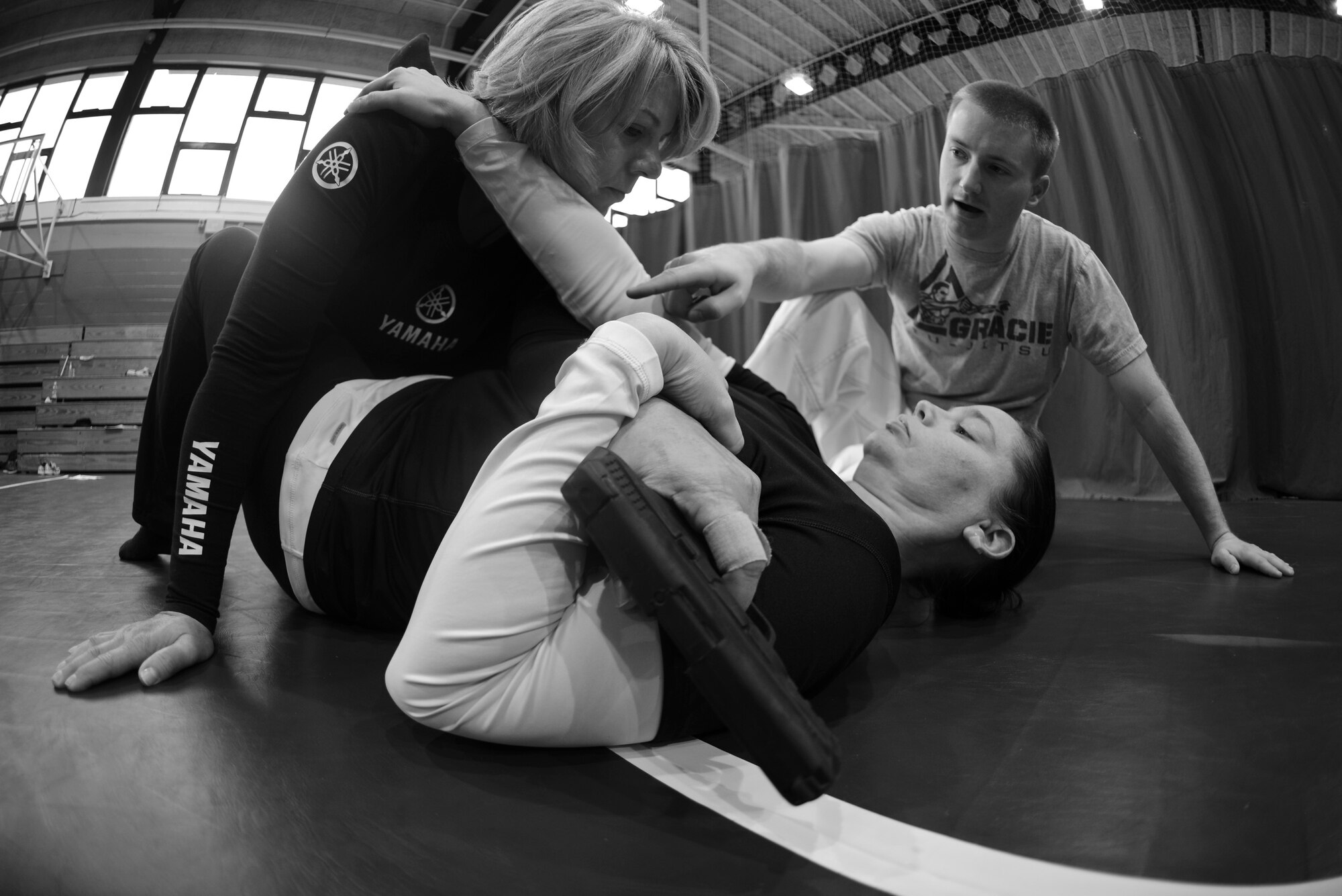 U.S. Air Force Staff Sgt. Matthew McConnell, right, 83rd Network Operations Squadron Detachment 4 plans and integration NCO and deputy director of Kaiserslautern Military Community Gracie Defense System, Ramstein Air Base, Germany, gives advice to Gracie Defense System students during a self-defense class Sept. 18, 2015, at the Northside Fitness Center on RAF Mildenhall, England. The students were practicing a defensive technique used to remove a weapon from an attacker. (U.S. Air Force photo by Staff Sgt. Micaiah Anthony/Released)