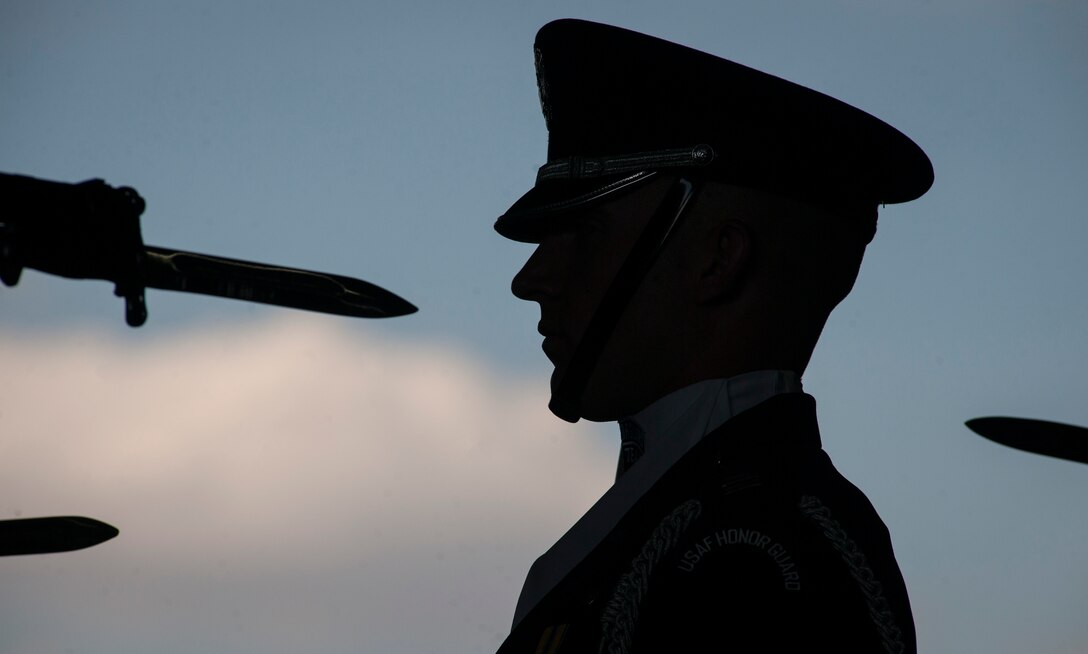 Capt. Cahn Wadhams, U.S. Air Force Honor Guard’s Drill Team commander, stands at the position of attention as other drill team members perform precise weapon maneuvers inside hangar 3 on Joint Base Andrews, Md., during the 2015 Air Show, Sept. 19. (U.S Air Force photo by Airman 1st Class Philip Bryant/Released) 

