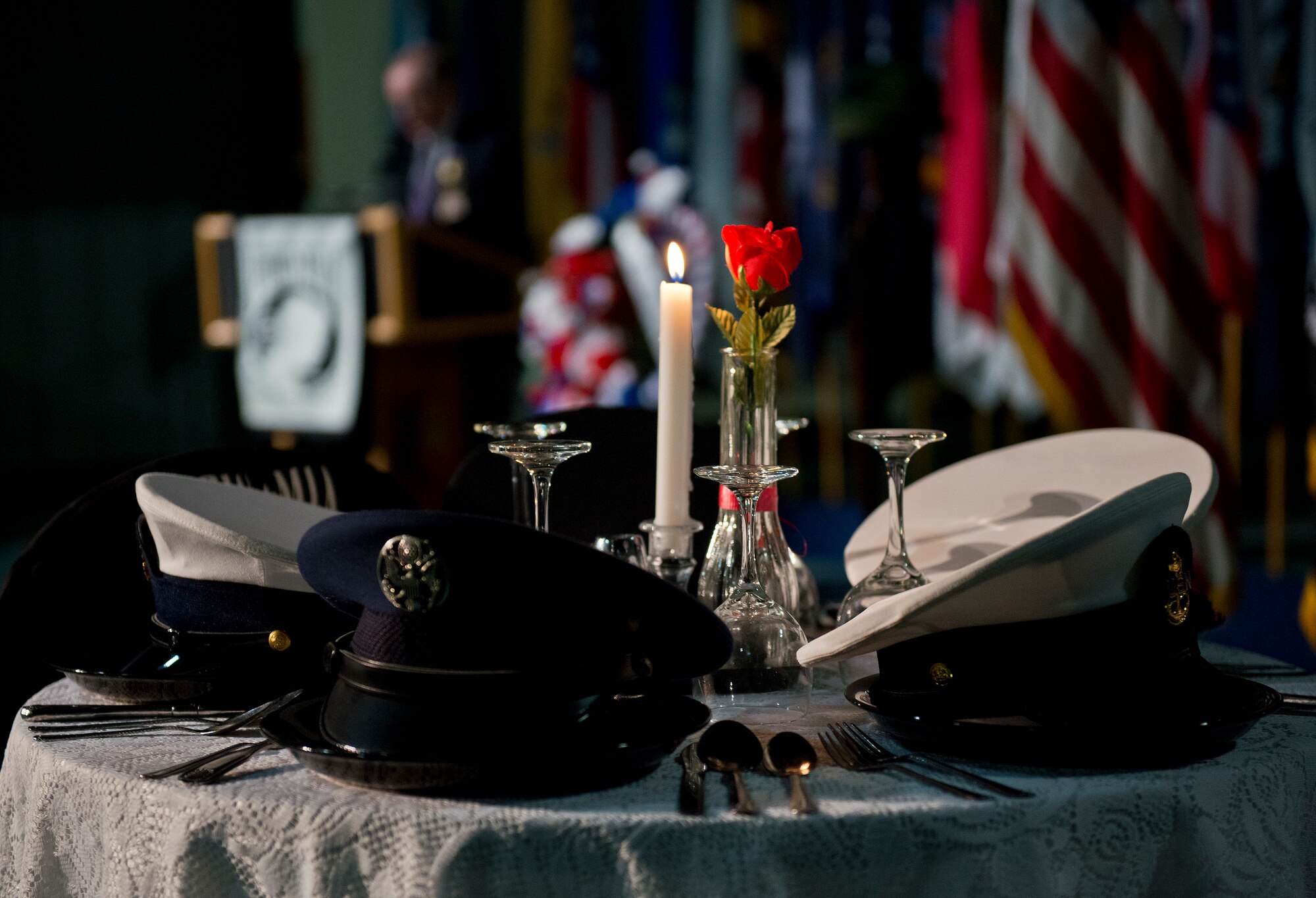 A candle burns on the POW/MIA table as guest speaker, Patrick Little, addresses the crowd at the remembrance ceremony Sept. 18 Eglin Air Force Base, Fla.  The ceremony paid tribute to those military members who have yet to return home from defending America. The event featured tributes, guest speakers and honor guard procedures. (U.S. Air Force photo/Samuel King Jr.)