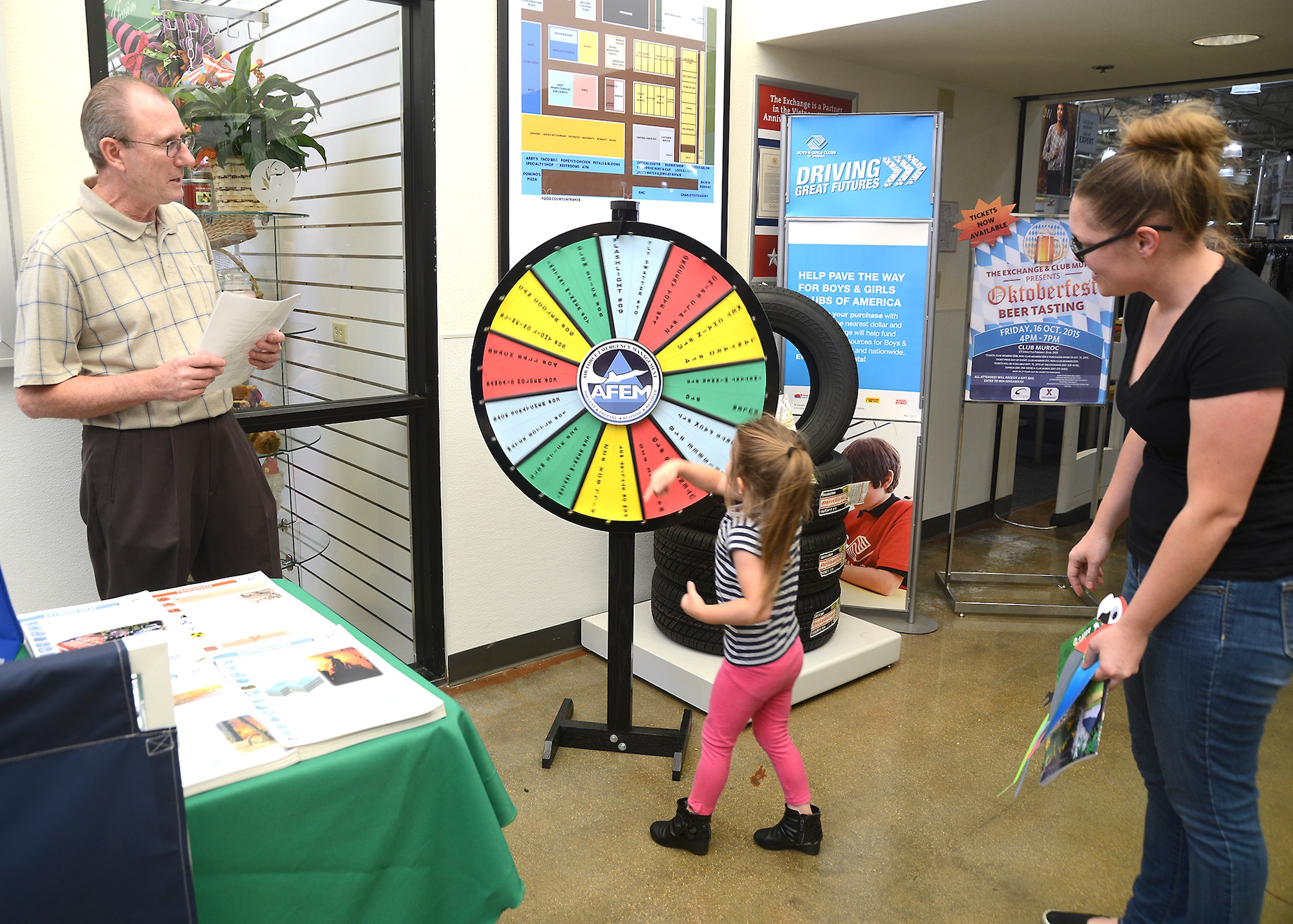 Russell Warner, 812th Civil Engineering Squadron, Emergency Management specialist, lets a young woman spin the Air Force Emergency Management Wheel to get a prize and an emergency preparedness trivia question. When is an earthquake most likely to occur? Answer: Anytime. September is National Preparedness Month. (U.S. Air Force photo by Kenji Thuloweit)