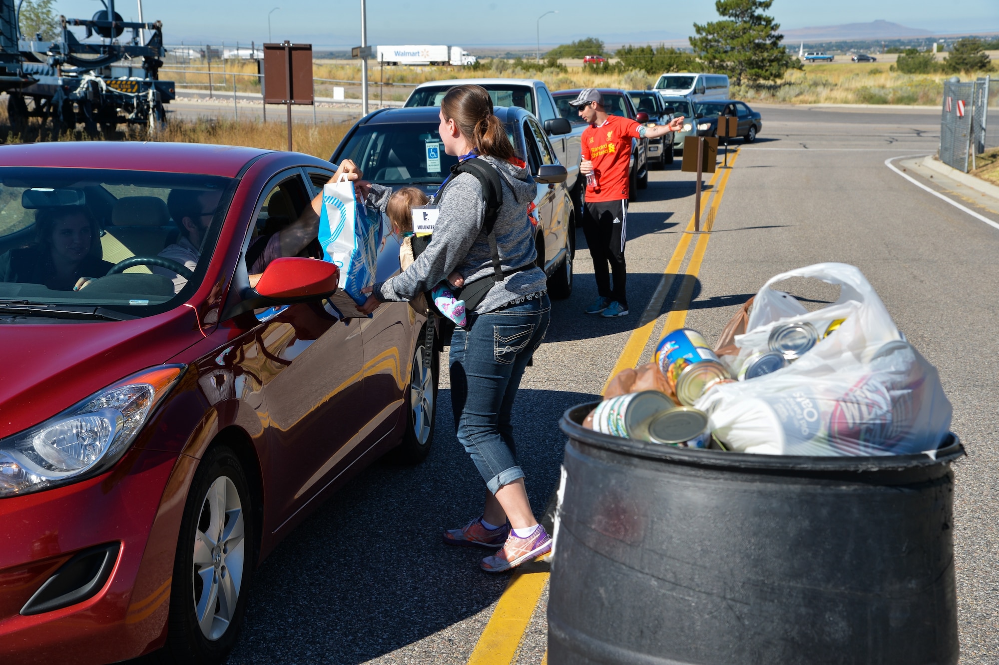 Senior Airman Kylee Reed grabs a bag of donated non-perishable food items while her husband, Derek Bender, directs an event goer to a parking space during the Wings and Wheels Car Show and Food for Life Event held at the Hill Aerospace Museum, Sept. 19, 2015. Food donations collected during the event will be used to replenish the Hill Air Force Base Airman's Attic food pantry. The Airman's Attic food pantry provides food items to active-duty military, retirees and off-base community support agencies. (U.S. Air Force photo by R. Nial Bradshaw)