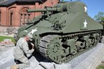 New York Army National Guard Spc. Jonathon Bishop, Co. B, 427th Brigade Support Battalion, attaches a clevis fastener on a refurbished World War II-era M4A3 Sherman tank on permanent display at the New York State Military Museum in Saratoga Springs, Sept. 15, 2015. National Guard Soldiers working full time at the Maneuver Area Training Equipment Site, or MATES, at Fort Drum, spent the past 22 months refurbishing and repainting the tank in their spare time. 