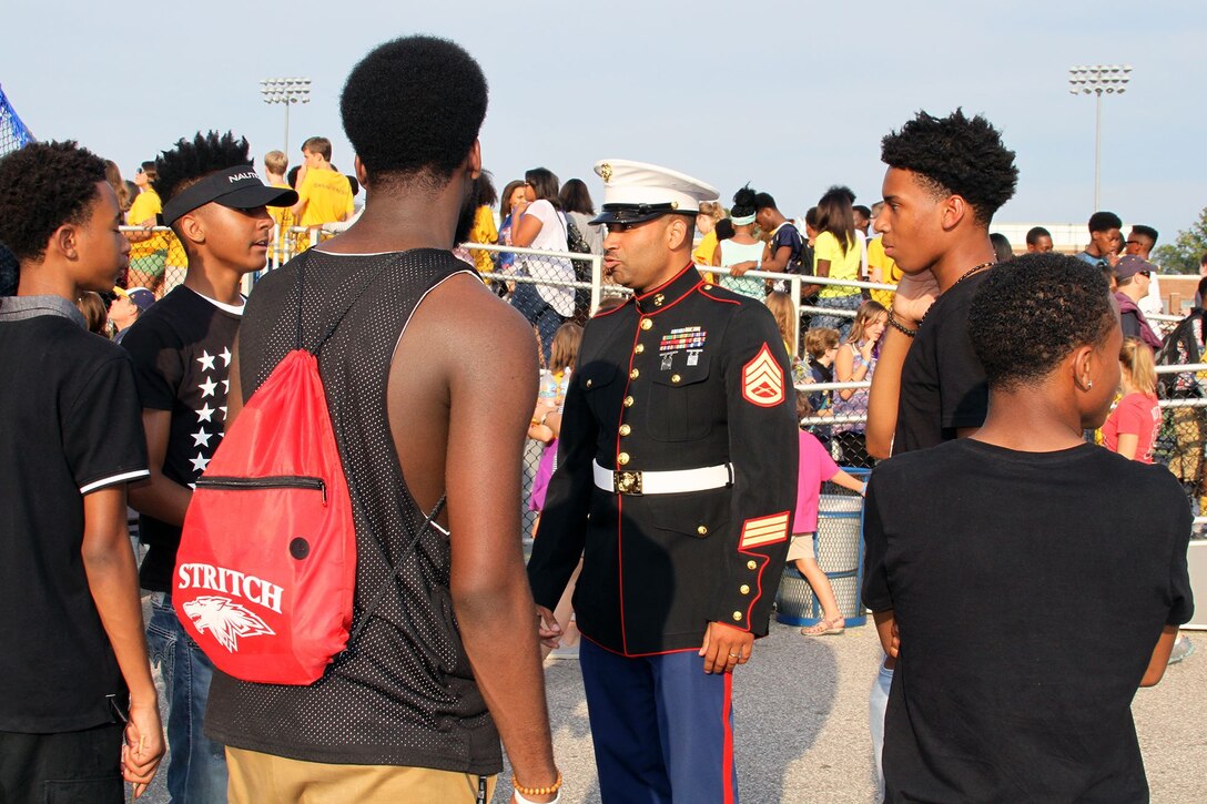 U.S. Marine Corps Staff Sgt. Ivory Carter III, a recruiter at Recruiting Sub-Station Cincinnati, engages a group of high school students during a football game at Walnut Hills High School, Aug. 28, 2015. Carter serves as a resource of information about the Marine Corps in the local community to provide young people with a promising opportunity after the completion of high school. (U.S. Marine Corps photo by Sgt. Jennifer Pirante/Released)