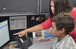 (Seated) Operation Warfighter Program Member Army Sgt. Palestine Fox learns about her new role as a DLA Energy program analyst and master planner from her on-the-job trainer, Logistics Management Specialist Christine Guillen, who will be Fox's primary trainer, providing guidance and shadowing until Fox is ready to take on the job herself. DLA Energy is one of the first organizations to hire a wounded warrior through the Operation Warfighter Program.