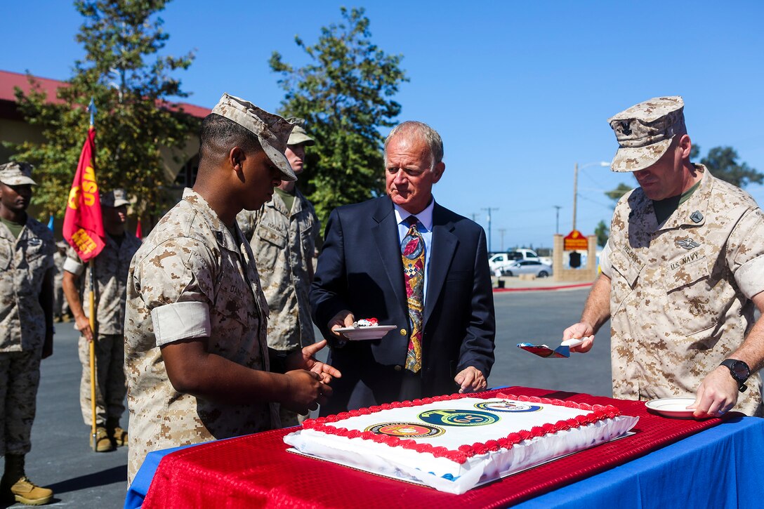 A former U.S. Navy Corpsman presents the first piece of cake to the youngest Corpsman during a cake-cutting ceremony while celebrating the 65th anniversary of Field Medical Training Battalion West, aboard Marine Corps Base Camp Pendleton, Calif., Sept. 18, 2015. FMTB-West opened its doors in the fall of 1950 and has trained young Sailors on life-saving techniques utilized on battlefields throughout history. The celebration was part of the graduation ceremony of Field Medical Service Technician Class 2015-040. (U.S. Marine Corps Photo by Sgt. Rick Hurtado / Released).