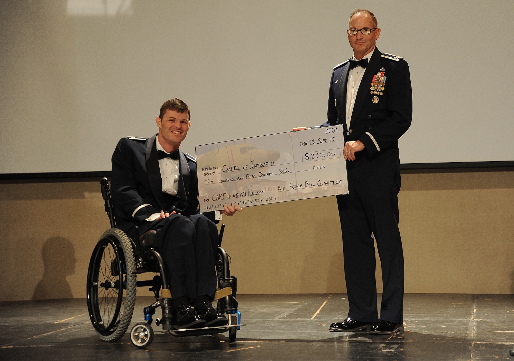U.S. Air Force Col. Michael L. Downs, 17th Training Wing Commander, awards Capt. Nathan Nelson, 24th Special Operations Wing Special Tactics intelligence officer, with a check for the Center of Intrepid during the Air Force Ball at the McNease Convention Center in San Angelo, Texas, Sept. 18, 2015. One of the missions for the Center of Intrepid is to provide rehabilitation for Operation Iraqi Freedom and Operation Enduring Freedom casualties who have sustained amputations, burns or functional limb loss.  (U.S. Air Force photo by Airman Caelynn Ferguson/Released)