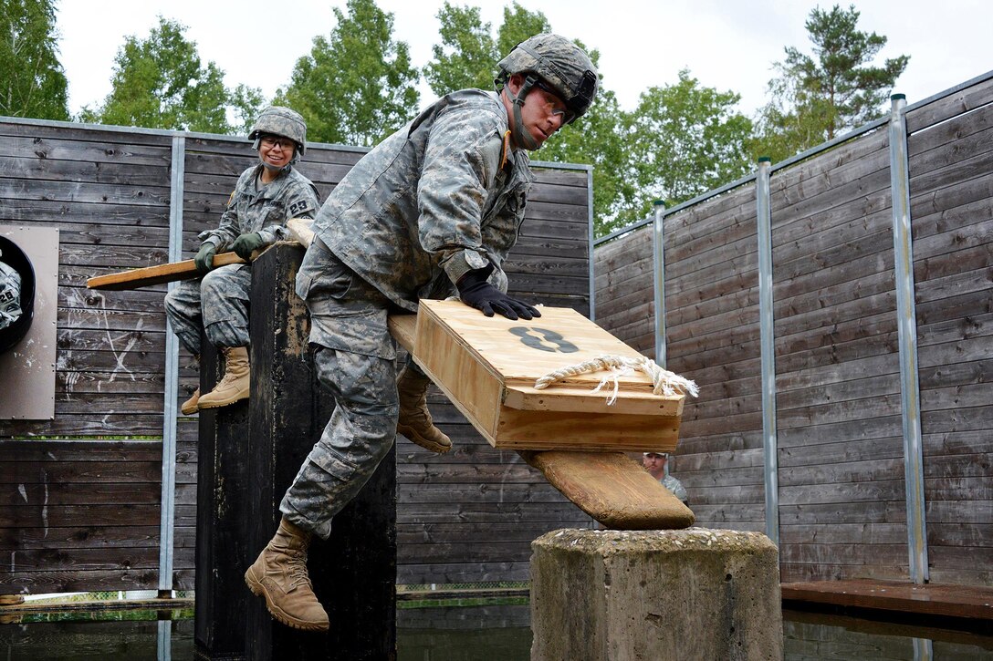 U.S. Army Spc. Julie Neff, foreground, moves a wooden box along a board over a water obstacle during the 2015 European Best Warrior Competition at the Grafenwoehr Training Area in Germany, Sept. 14, 2015. Neff is assigned to the 5th Battalion, 148th Aviation Regiment.


