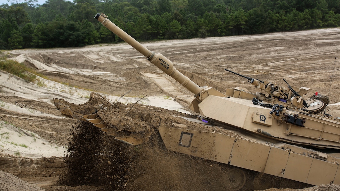 Marines with Alpha Company, 2nd Tank Battalion, drive an M1 Abrams tank over a dirt berm during a vehicle breaching exercise aboard Engineer Training Area 2, Camp Lejeune, N.C., Sept. 17, 2015. Marines with Mobile Assault Company, 2nd Combat Engineer Battalion, utilized their vehicles to breach a path through the berm for the tanks to follow.