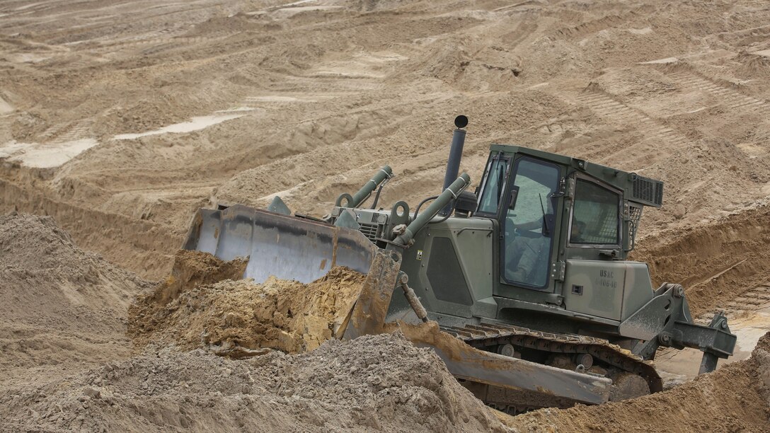 A Marine with Mobile Assault Company, 2nd Combat Engineer Battalion, plows dirt in a bulldozer during a vehicle breaching exercise aboard Engineer Training Area 2, Camp Lejeune, N.C., Sept. 17, 2015. The objective for the bulldozer was to reduce the berm to a terrain more capable for the continuous track of tanks with 2nd Tank Battalion. 