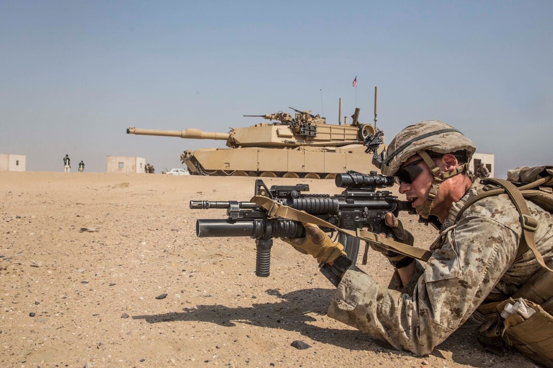 KUWAIT (Aug. 28, 2015) U.S. Marine Cpl. Jeffery Salois aims at a target while conducting mechanized squad attacks in an urban environment. Salois is a team leader with Kilo Company, Battalion Landing Team 3rd Battalion, 1st Marine Regiment, 15th Marine Expeditionary Unit. During the training, Marines learned how to incorporate an M1A1 Abrams tank in squad attacks in an urban environment. Elements of the 15th MEU are ashore in Kuwait for sustainment training to maintain and enhance the skills they developed during their pre-deployment training period.  The 15th MEU is embarked with the Essex Amphibious Ready Group and are deployed to maintain regional security in the U.S. 5th Fleet area of operations. (U.S. Marine Corps photo by Sgt. Emmanuel Ramos/Released)